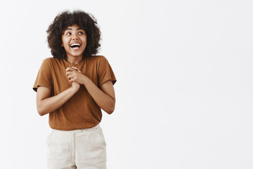 Studio shot of excited and dreamy good-looking fit African American female with afro hairstyle...