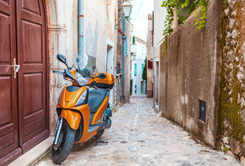 Fototapeta na wymiar Scooter in narrow street with stone houses, Croatia