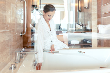 Woman in luxurious hotel bathroom letting water in the bathtub in animation of a relaxing...