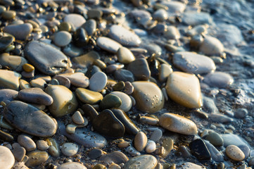 pebble stones on the sea beach, the rolling waves of the sea with foam