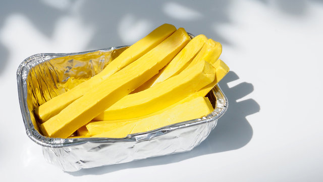 French fries in foil packaging is under the tree has shadow nature art concept