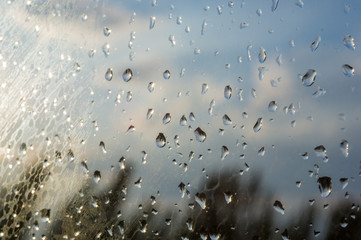 raindrops on window glass on background of cloudy sky