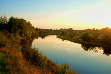 Fototapeta na wymiar Sunrise reflected in calm river water surface