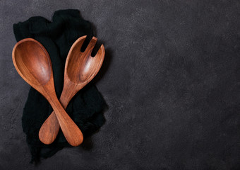 Vintage kitchen wooden utensils over black cloth on stone table background. Top view. Space for text