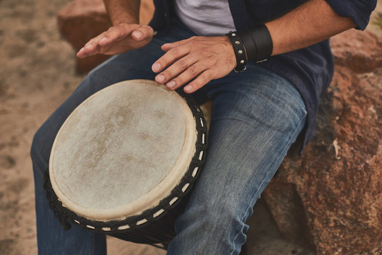 Music improvisation. Close up of male hands playing music using djembe