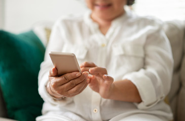 Happy Asian Senior Woman using smart phone at her house.