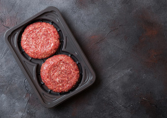 Plastic tray with raw minced home made grill beef burgers with spices and herbs. Top view.