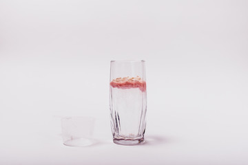 Undissolved pink whey protein in glass of water