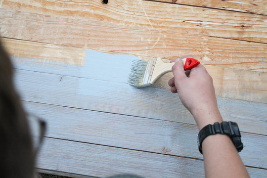 master paints old wooden floor with gray brush. background