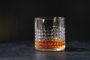Glass of scotch whiskey standing on black marble table. Alcohol drink.