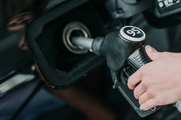 Close up woman hand holding petrol pump nozzle while servicing the contemporary vehicle outdoor