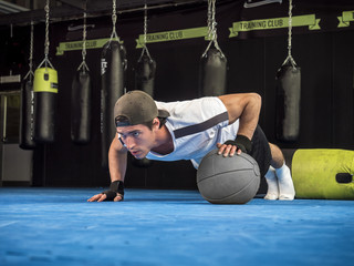 Handsome muscular young man exercising pecs in gym with push-ups