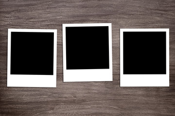 three blacked-out instant photo print templates on rustic wooden background