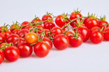 Branches of red organic fresh cherry tomatoes on a white background. Top view