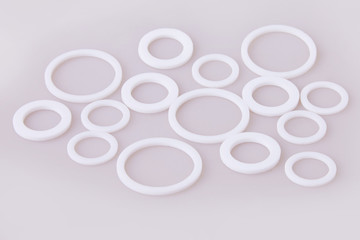 White hydraulic and pneumatic o-ring seals of different sizes scattered a white background. Rubber rings. Sealing gaskets for hydraulic joints. Rubber sealing rings for plumbing. 