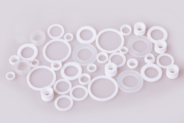 White hydraulic and pneumatic o-ring seals of different sizes scattered a white background. Rubber rings. Sealing gaskets for hydraulic joints. Rubber sealing rings for plumbing. Top 