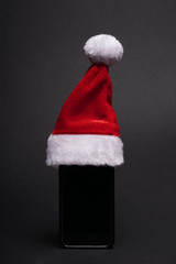 Obraz na płótnie Canvas smartphone with santa claus hat as christmas present