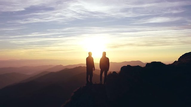 The silhouette of a man and a woman on the mountain with a beautiful sunrise
