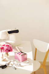 Workplace for sewing and needlework in a bright room with white furniture.