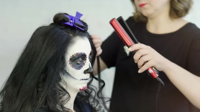 Halloween party. Professional hairdresser doing hairstyle with curls for young dark woman. 4K