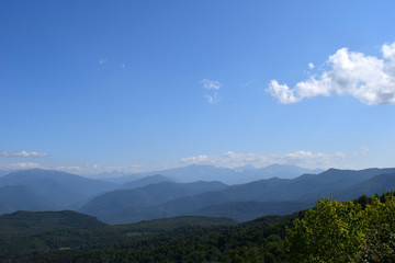 Green mountains and blue sky. Beautiful summer landscape with multilayered hills, fog and forest. Main Caucasian ridge, Adygea.