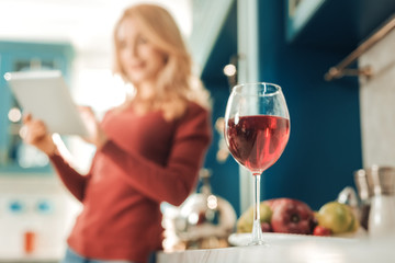 Red wine. Silhouette of pretty female that using her gadget for checking news