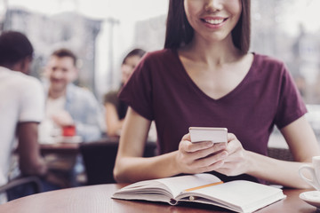 Having break. Positive delighted girl keeping smile on face while typing message