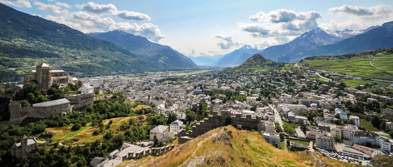 Panorama over Sion, the capital of the Canton Valais in Switzerland. Photo was taken on the hills surrounding Sion on which two castles are located: the Tourbilllon.and Valere. - obrazy, fototapety, plakaty