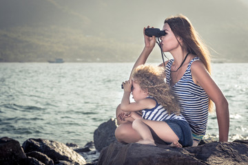 Little girl and mother looking far away with binoculars