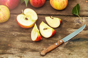 Red apple sliced and knife on old wooden table