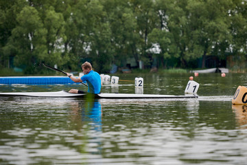 Fototapeta na wymiar The young athlete sailed to the finish in a kayak one of the first during summer watersport