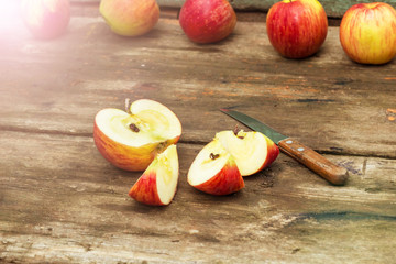 Red apple sliced and knife on old wooden table