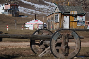 Fototapeta premium Traditional and ancient carriage wagon infront of a ger and cottage or barn with snow in autumn fall at Terelji National Park, Mongolia, Asia