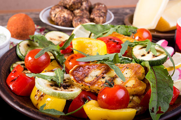 Set collection of cheese and snacks. Grilled halloumi, pepper, zuccini, tomato cherry and radish over on old wooden rustic background.