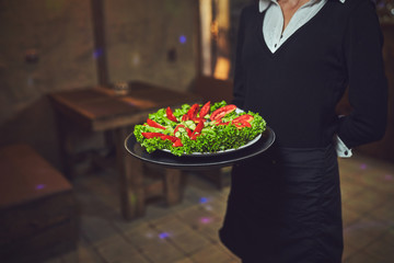 Waiters carrying plates with food, in a restaurant.