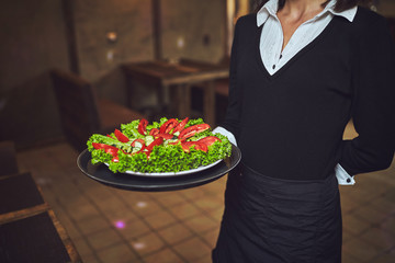 Waiters carrying plates with food, in a restaurant.