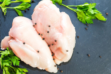 Raw chicken breasts with spices on chalk board