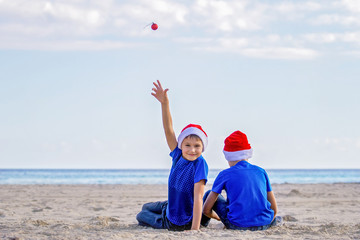 Christmas holiday. Kids in red Santa hats at sunny beach