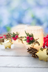 Christmas decoration - decorated candles,red berries,cones and golden stars on white wooden table on background of blue bokeh