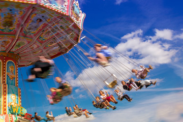 Fototapeta premium Carousel in motion blur at at the biggest folk festival of the world - the Oktoberfest in Munich - blue sky with white clouds