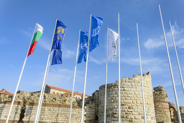 Entrance of the nessebar city in Bulgaria, with ruins of a  stronghold and flags.