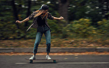 A girl on a skateboard is riding at high speed