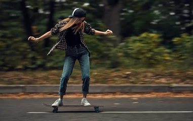 Zelfklevend Fotobehang A girl on a skateboard is riding at high speed © Bogdan