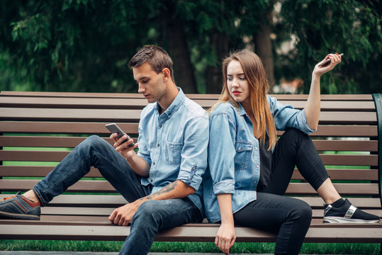 Phone Addiction, Young Couple On The Bench In Park