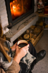 Obraz na płótnie Canvas Woman drinking mulled wine by the fireplace