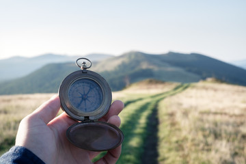 Man with compass in hand on mountains road. Travel concept. Landscape photography
