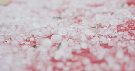 closeup of hailstones on red car after strong hailstorm