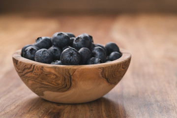 Fresh blueberries in wood bowl on table slightly toned