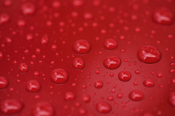 Closeup rain drops on red car with hydrophobic coating