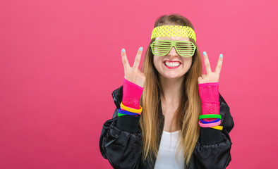 Woman in 1980's fashion giving the peace sign on a pink background